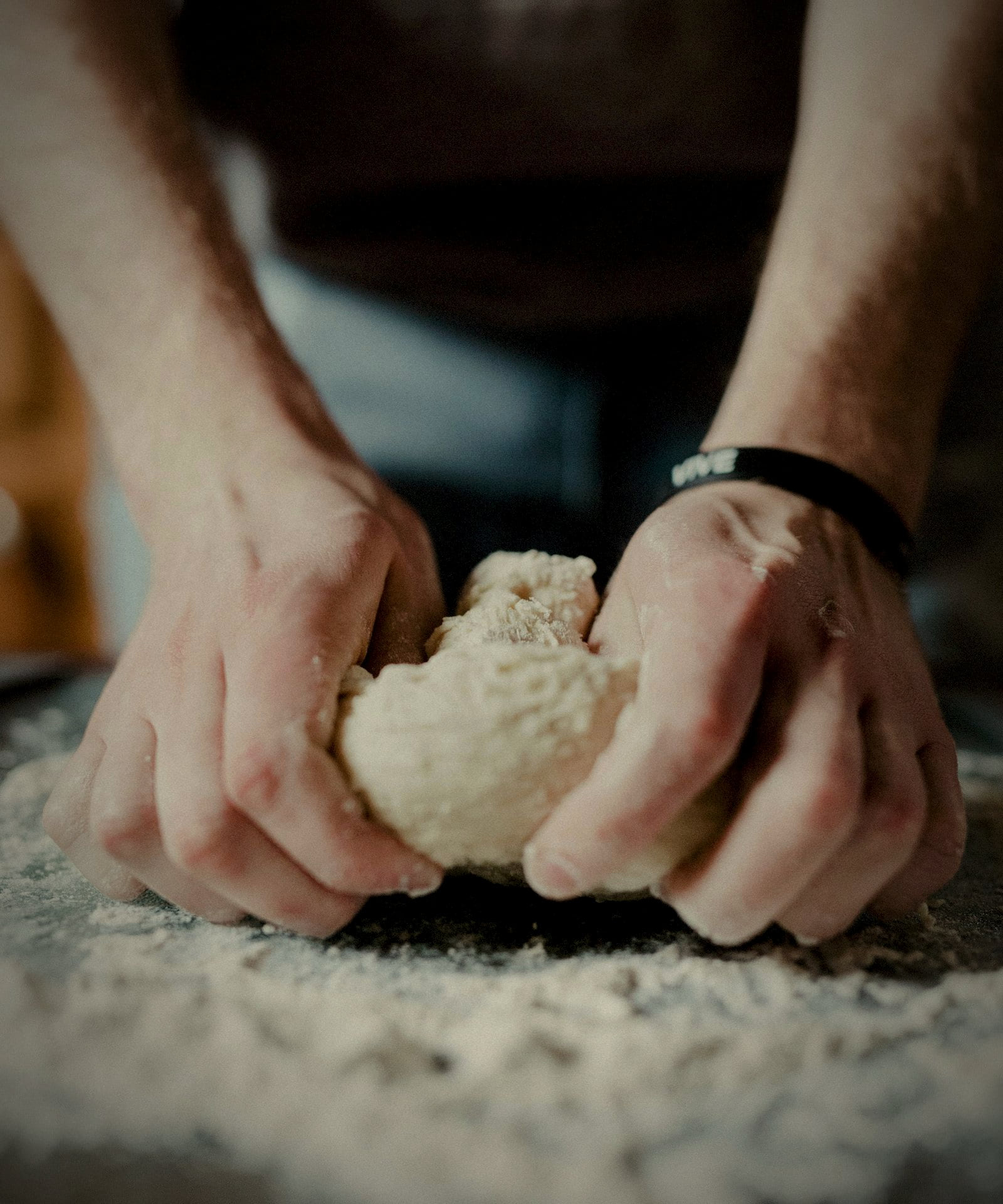 Hands kneading dough on a floured wooden surface