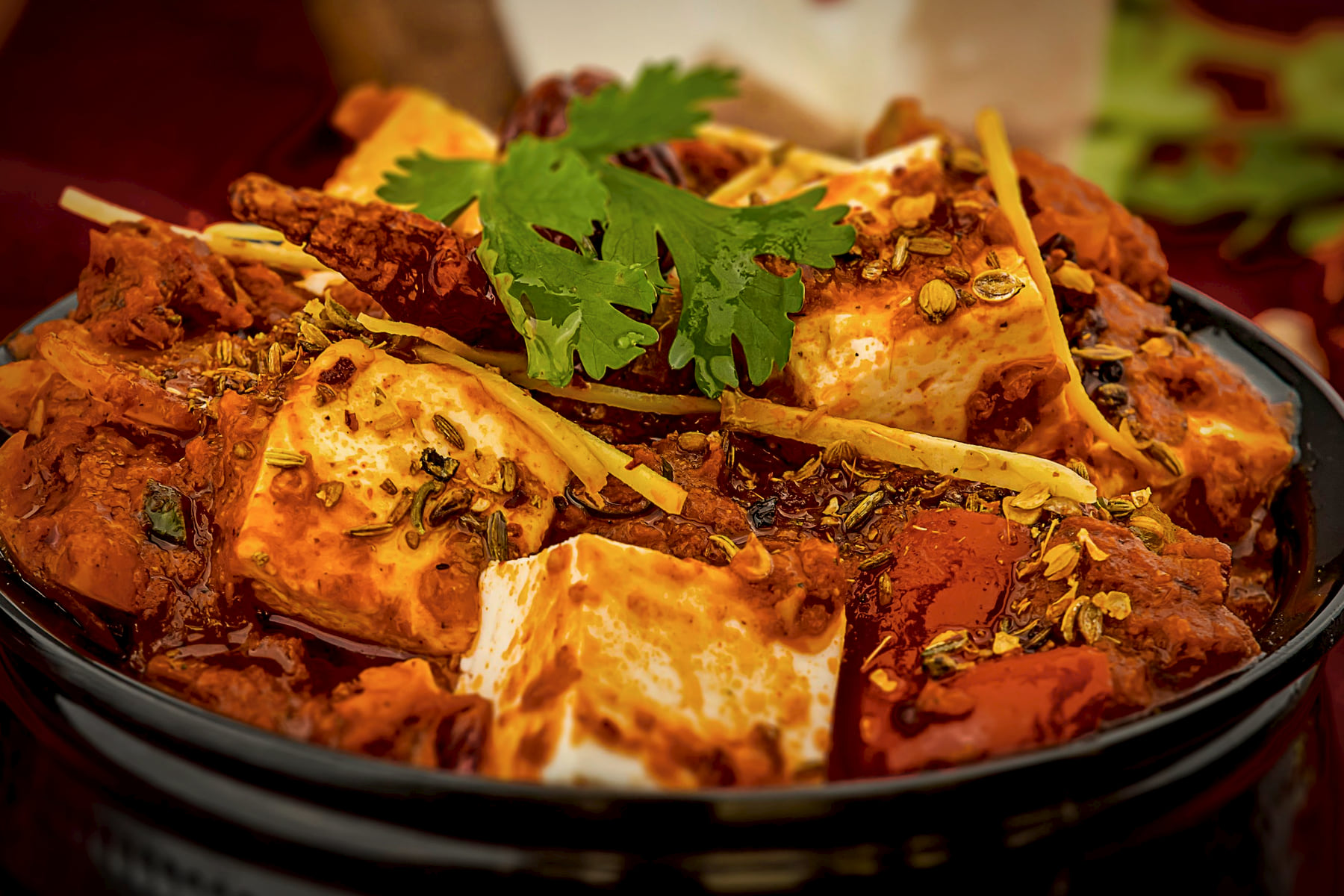Paneer in a deep mahogany gravy in a dark hammered handi, finished with ginger julienne and coriander