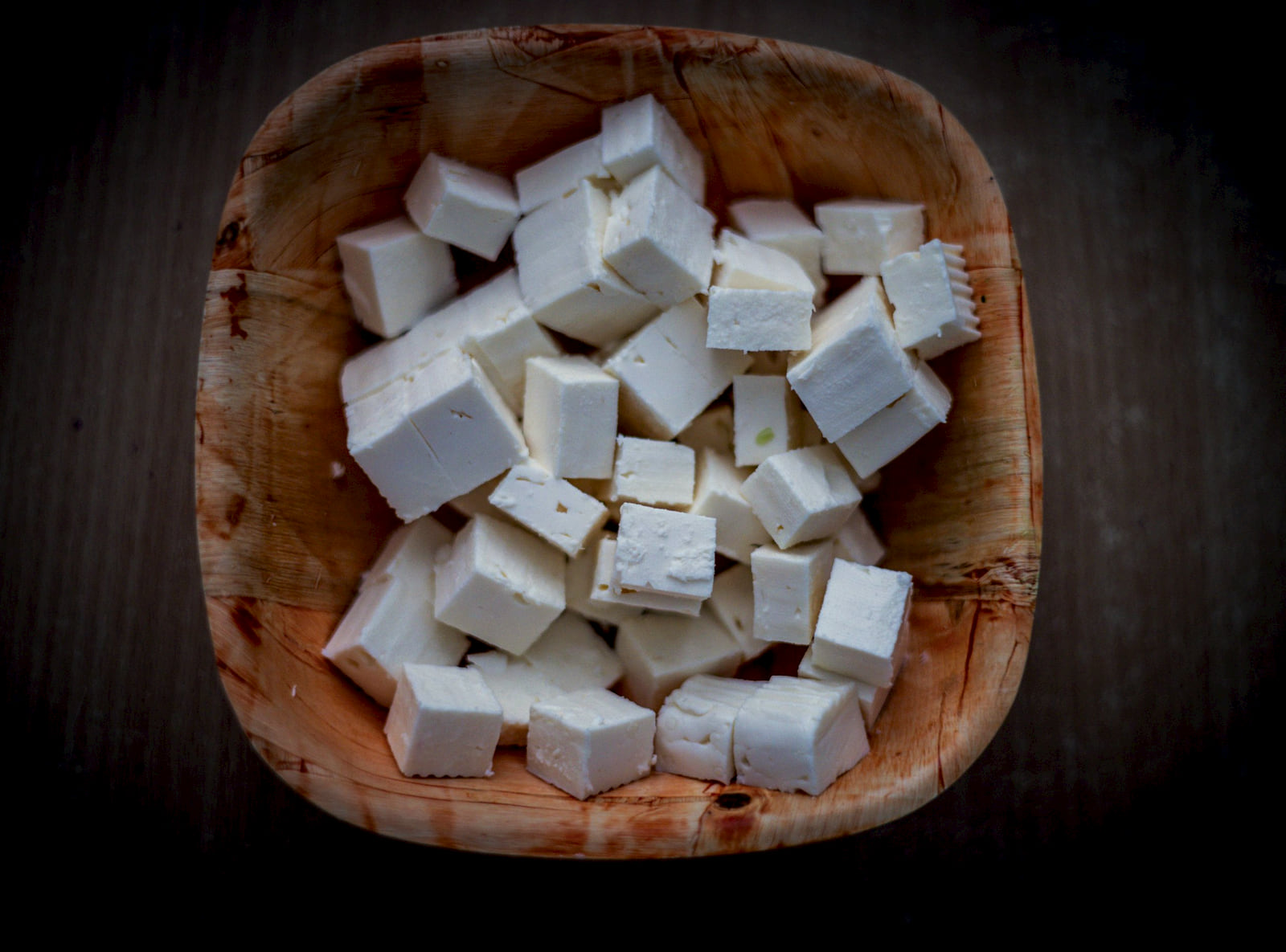 Cubes of fresh paneer in a carved wooden bowl